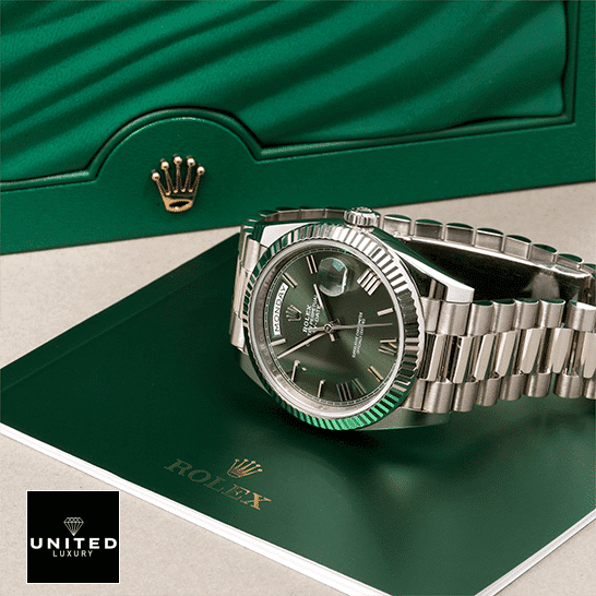 Rolex Day-Date 228239-0033 Rolex Day-Date 228239-0033 Romen Numerial Olive Green Dial Replica in front of Rolex Box