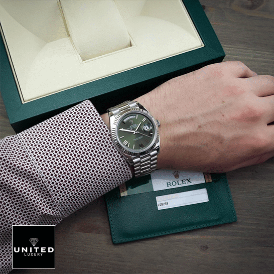 Rolex Day-Date 228239-0033 Rolex Day-Date Olive Green 228239 Replica Rolex Box in front of on is arm